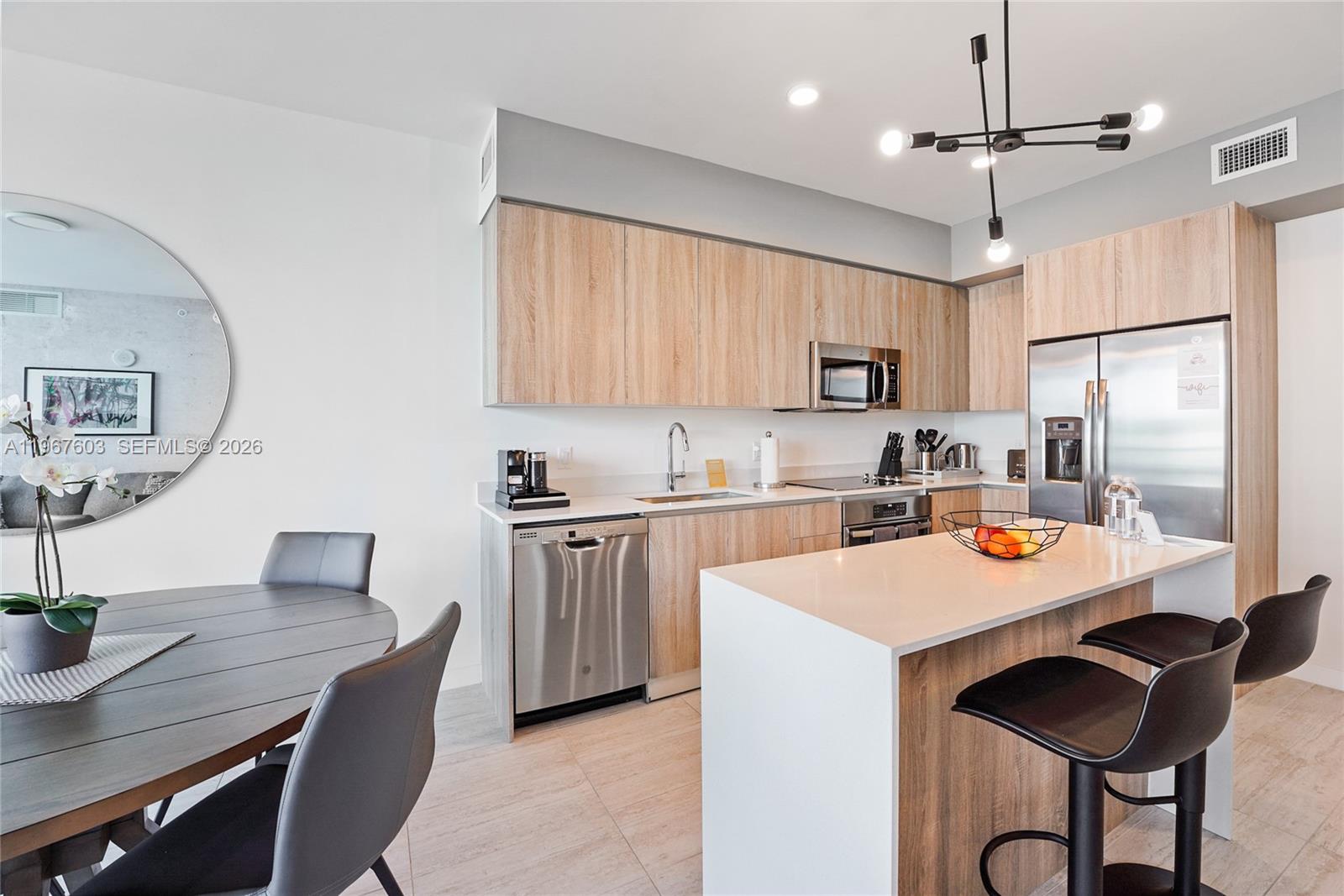 A modern kitchen features light wood cabinetry, stainless steel appliances, and a white quartz island — 3900 Biscayne Blvd # 218, Miami FL 33137, MIAMI, FL