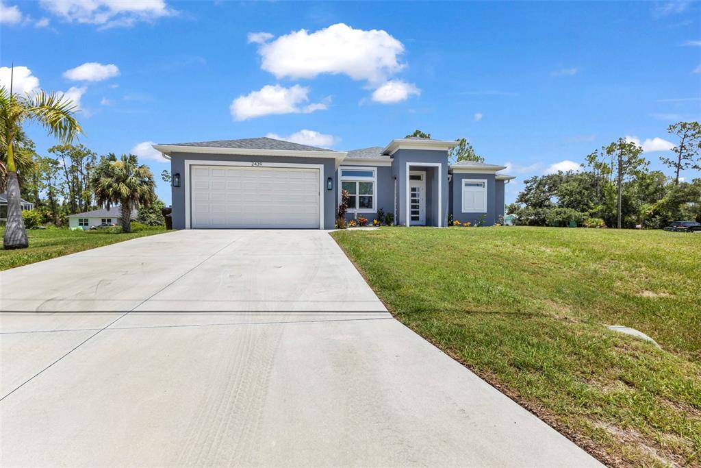A gray single-story house with a white garage door and a concrete driveway — 2439 WILBURN TERRACE, NORTH PORT, FL