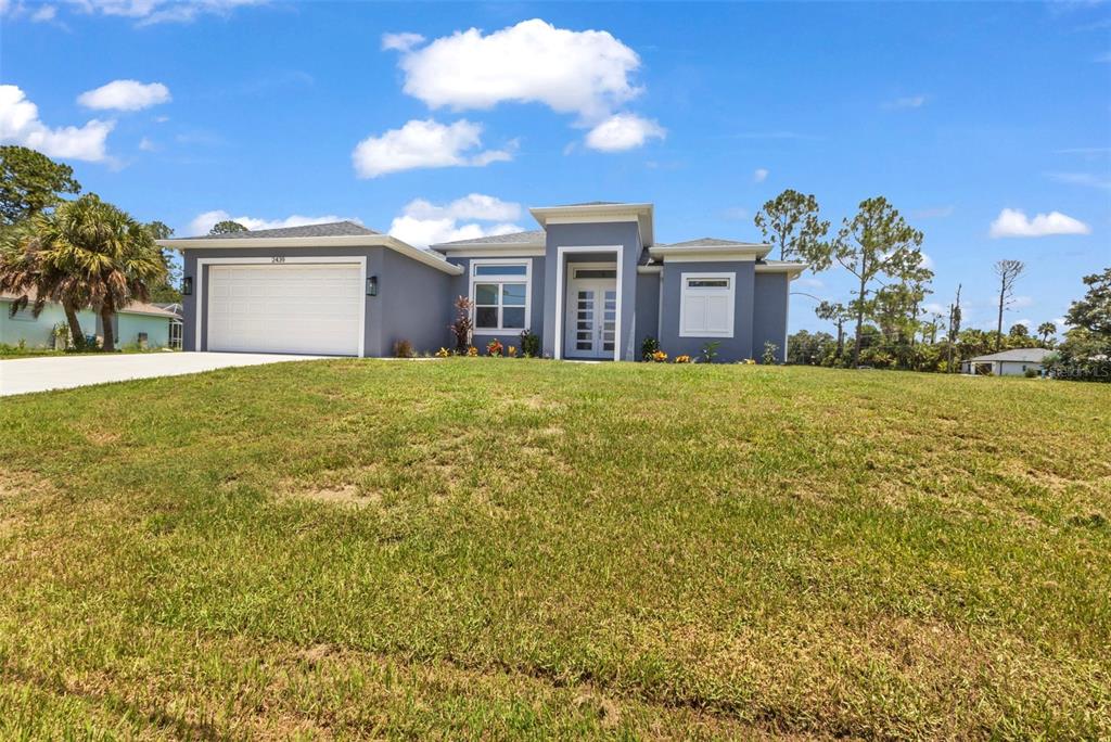 A single-story house with a gray exterior, a two-car garage, and a grassy front yard — 2439 WILBURN TERRACE, NORTH PORT, FL