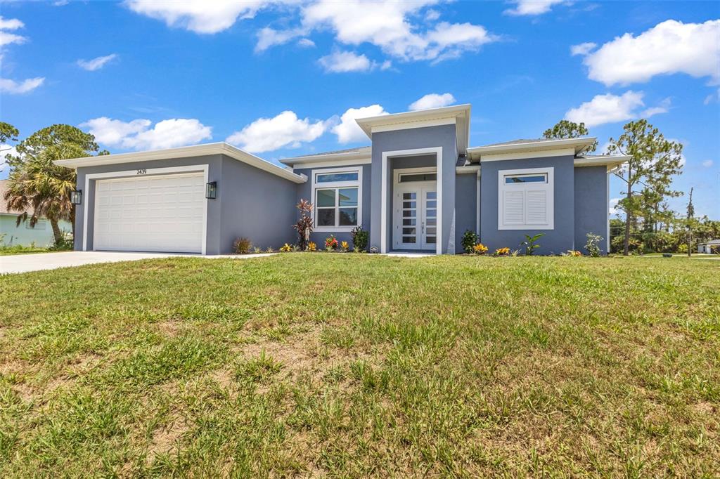 A single-story blue house with a white garage door and a central entryway — 2439 WILBURN TERRACE, NORTH PORT, FL