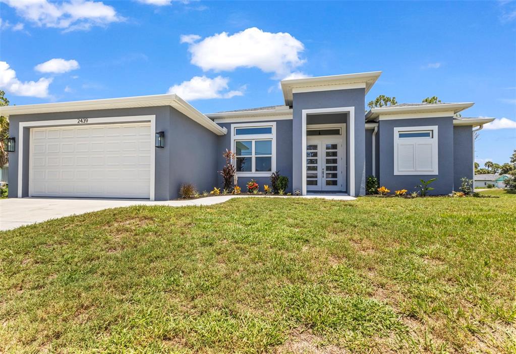 A single-story house with a gray exterior, a white garage door, and a front entrance — 2439 WILBURN TERRACE, NORTH PORT, FL