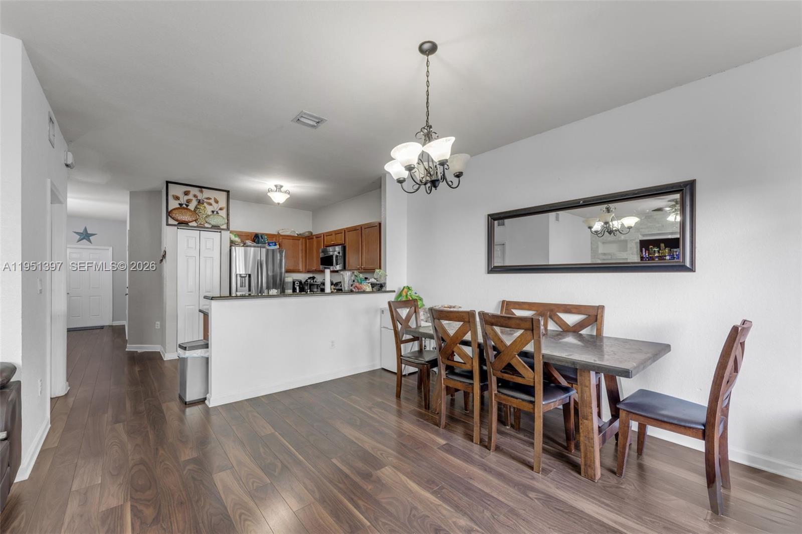 A dining area with a wooden table and chairs sits adjacent to an open kitchen — 22412 SW 89th Ave, Cutler Bay FL 33190, CUTLER BAY, FL