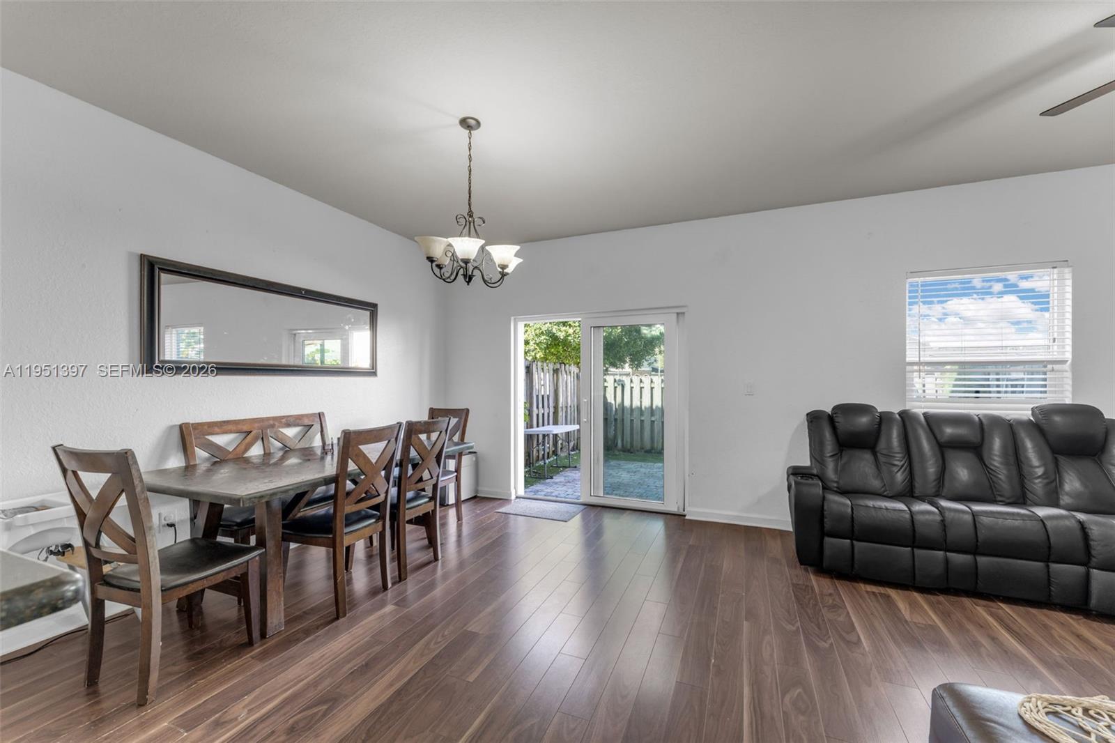 A dining area with a wooden table and chairs sits beside a living room sofa — 22412 SW 89th Ave, Cutler Bay FL 33190, CUTLER BAY, FL
