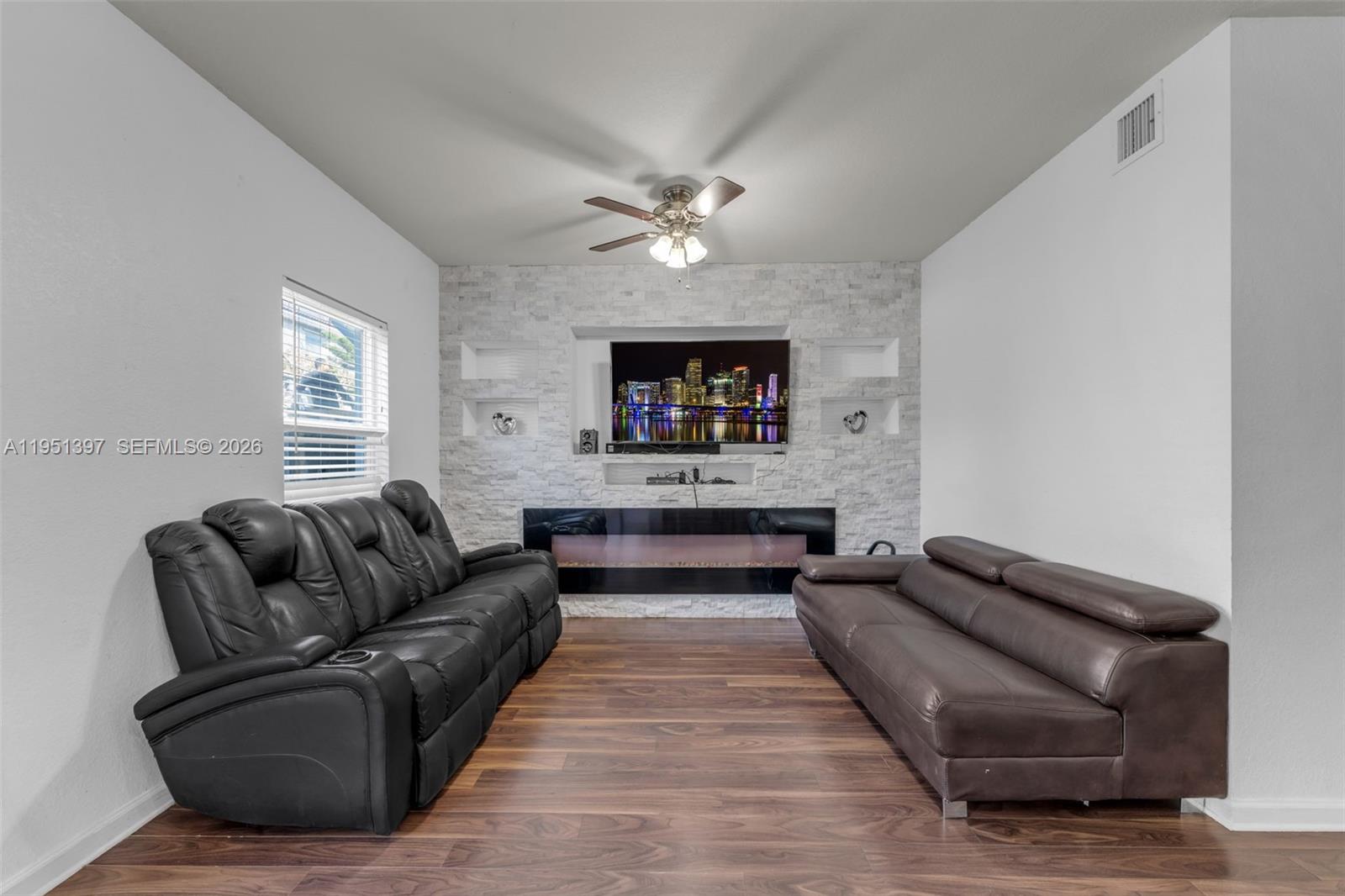 A living room features a stone accent wall with a fireplace, TV, and two sofas — 22412 SW 89th Ave, Cutler Bay FL 33190, CUTLER BAY, FL