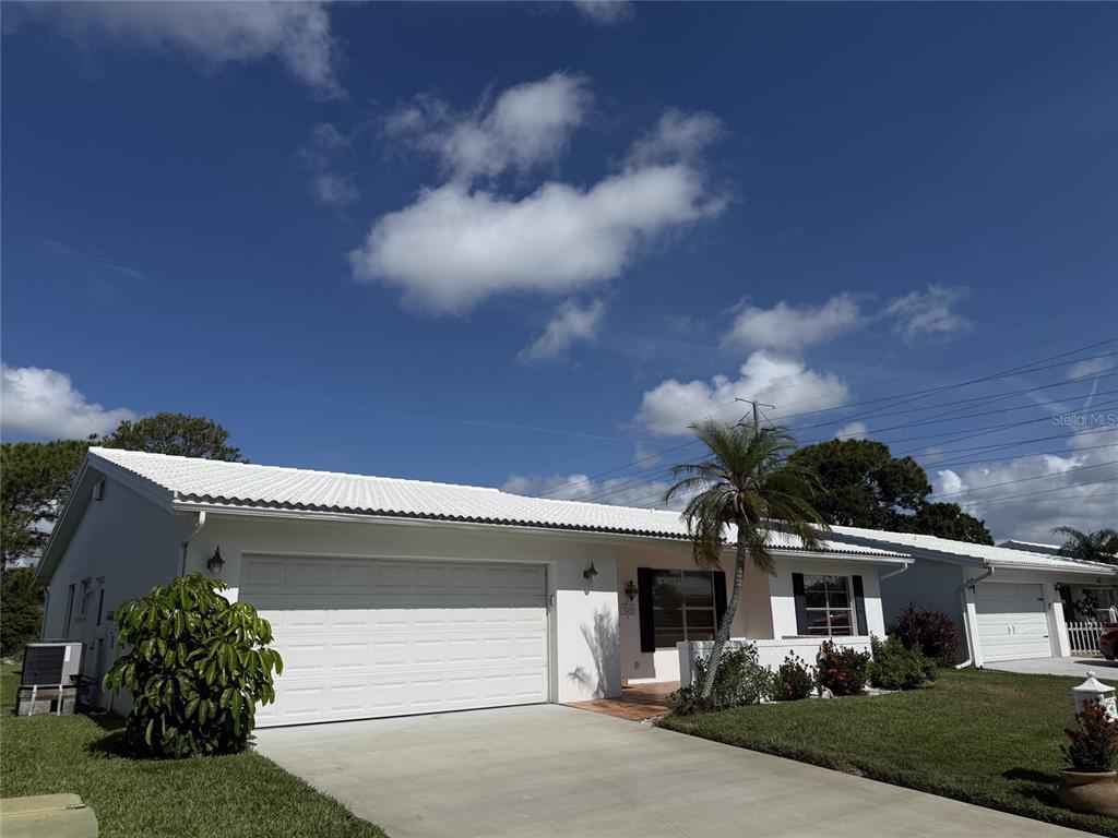 A white single-story house with a two-car garage and a palm tree in the front — 3455 MAINLANDS BOULEVARD S, PINELLAS PARK, FL