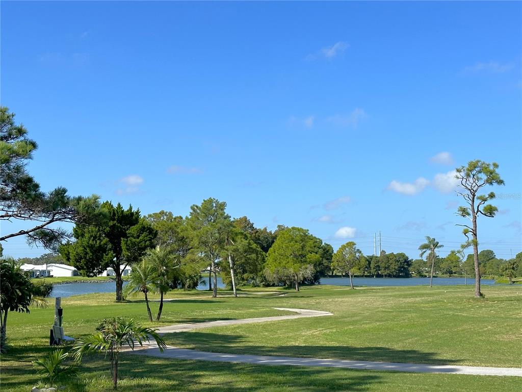 A paved path winds through a grassy golf course toward a lake and distant trees — 3455 MAINLANDS BOULEVARD S, PINELLAS PARK, FL