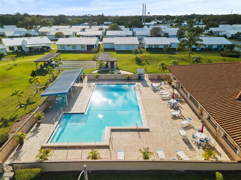 An aerial view of a community swimming pool with lounge chairs and a covered patio area — 3455 MAINLANDS BOULEVARD S, PINELLAS PARK, FL