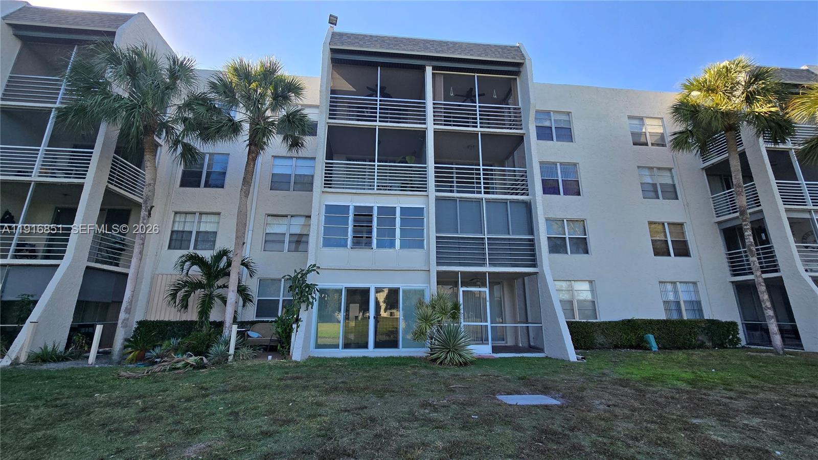 The exterior view shows a multi-story apartment building with screened balconies and palm trees — 9230 Lagoon Pl # 310, Davie FL 33324, DAVIE, FL