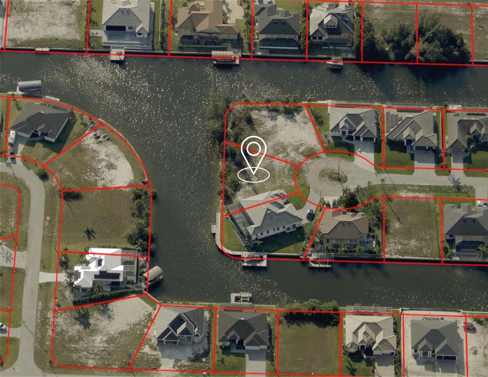 This aerial view shows a vacant waterfront lot and surrounding residential properties along a canal — 2316 NW 39TH AVENUE, CAPE CORAL, FL