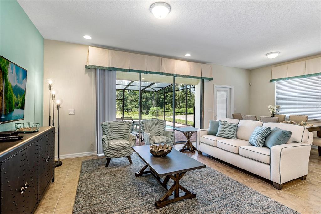 A living room features a white sofa, two patterned armchairs, and a sliding glass door — 8887 GENEVE COURT, KISSIMMEE, FL