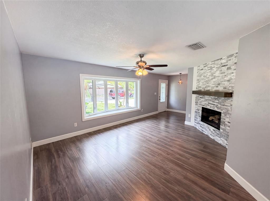 A living room features wood-look flooring, a large bay window, and a stone-faced fireplace — 4830 DUNBARTON DRIVE, ORLANDO, FL