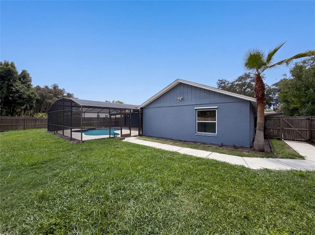 A blue house exterior features a screened-in pool, a concrete walkway, and a palm tree — 4830 DUNBARTON DRIVE, ORLANDO, FL