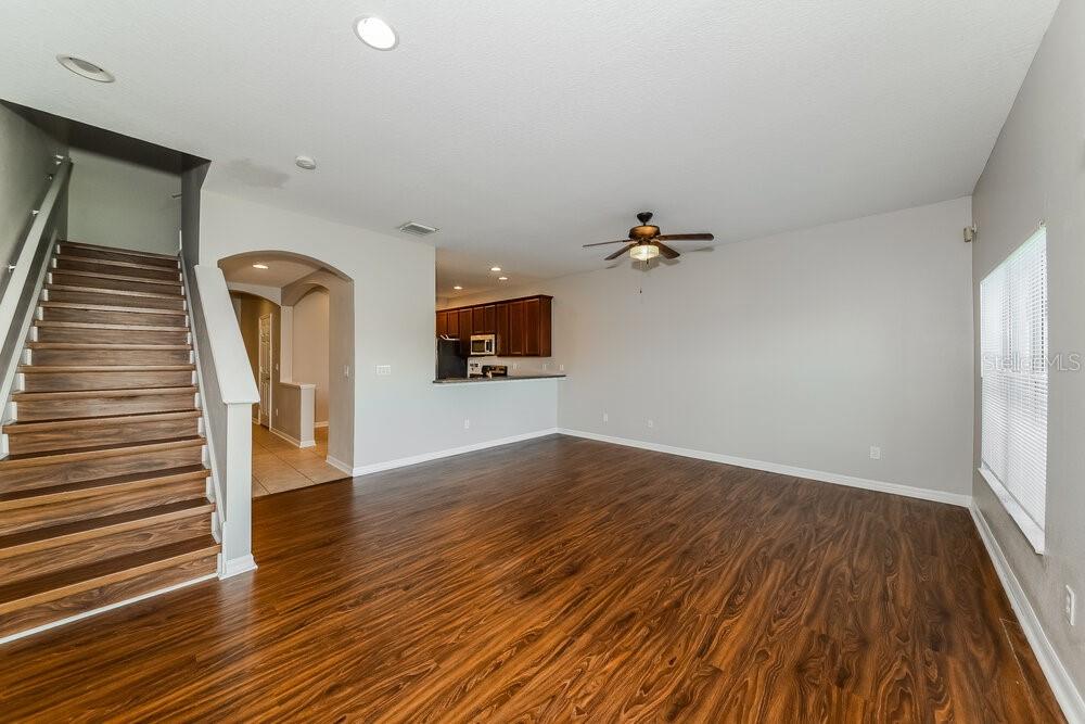 An open-concept living area features wood-look flooring, a staircase, and a kitchen with dark cabinets — 11510 84TH STREET CIRCLE E UNIT 102, PARRISH, FL