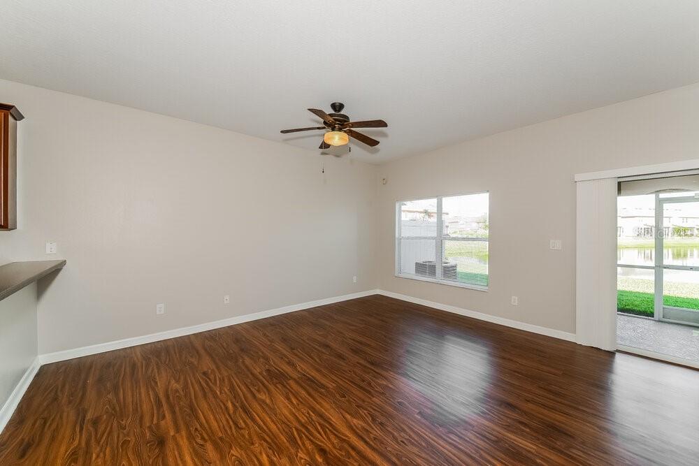 An empty living room with wood-look flooring, a ceiling fan, and a sliding glass door — 11510 84TH STREET CIRCLE E UNIT 102, PARRISH, FL