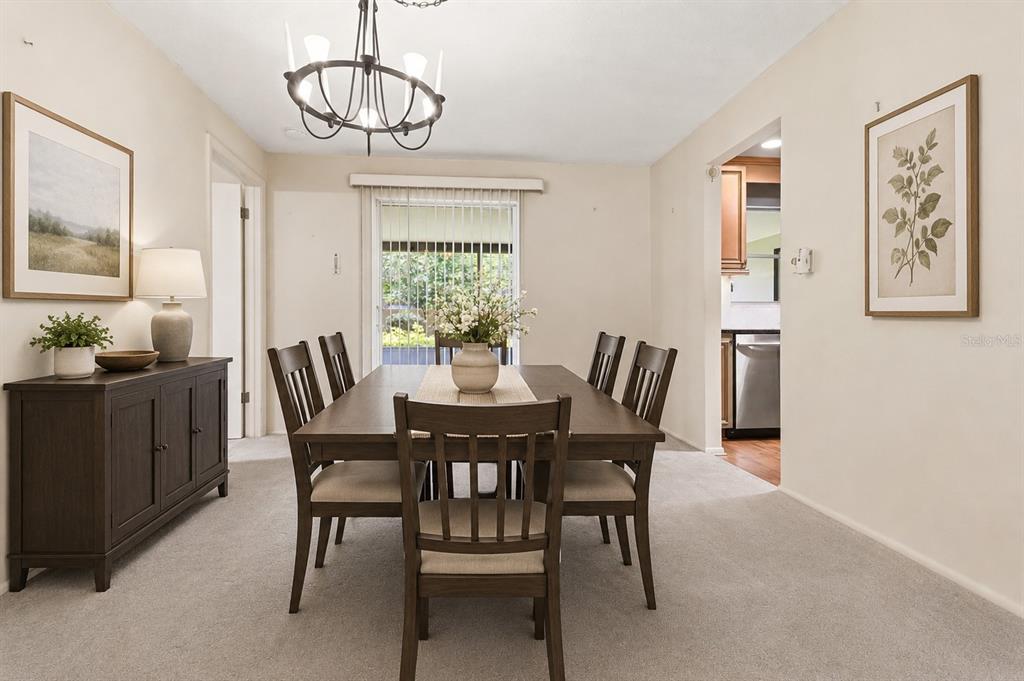 A dining room features a dark wood table and chairs, a sideboard, and carpeted floors — 1904 GRANADA COURT, CLEARWATER, FL