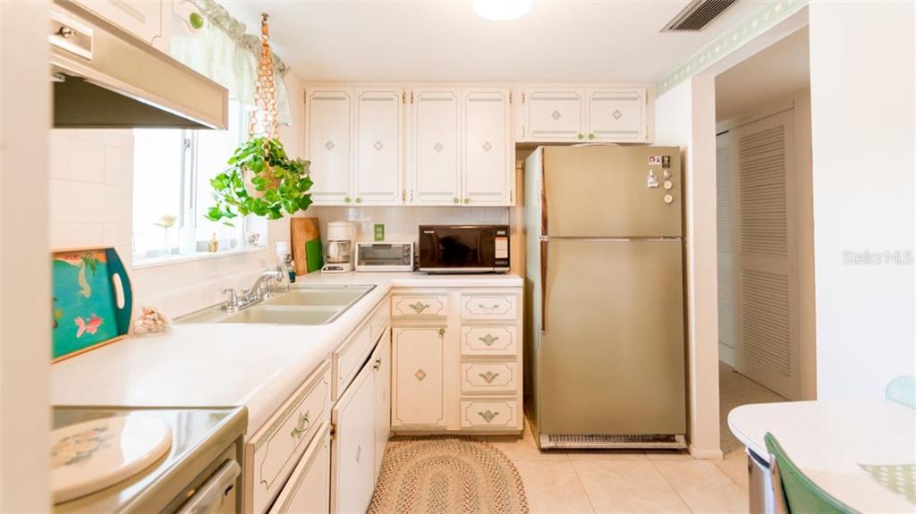 A kitchen with white cabinets, a stainless steel refrigerator, and a window above the sink — 1816 SUNNY DRIVE UNIT D21, BRADENTON, FL