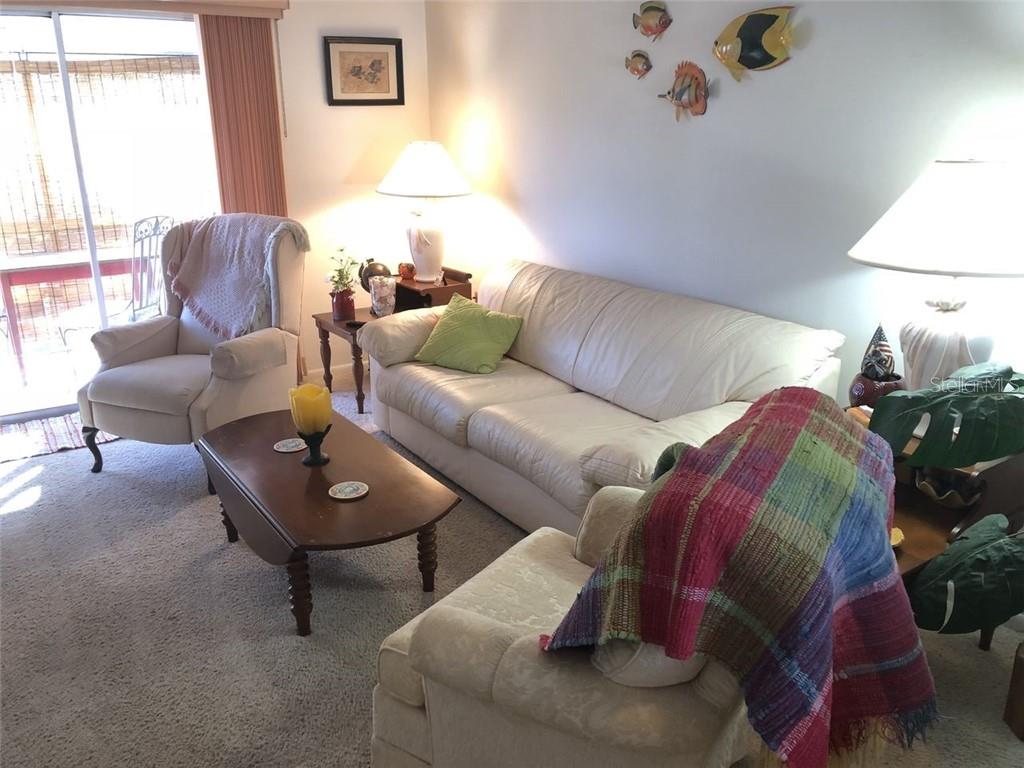 A living room features a white sofa, a recliner, a coffee table, and wall-mounted fish decor — 1816 SUNNY DRIVE UNIT D21, BRADENTON, FL