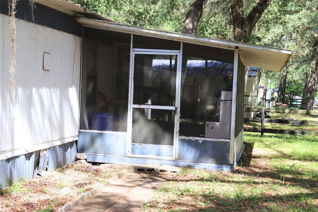A single-wide mobile home with a screened-in porch sits on a wooded, grassy lot — 2466 CR 401A, LAKE PANASOFFKEE, FL