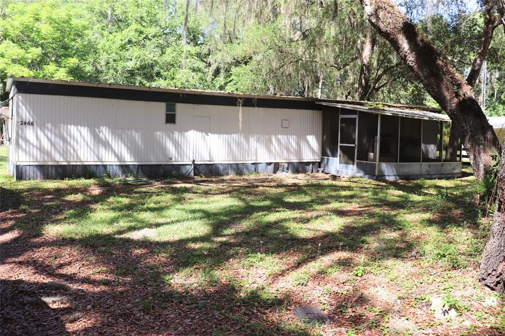 A mobile home features a screened-in porch with a metal roof and a concrete walkway — 2466 CR 401A, LAKE PANASOFFKEE, FL
