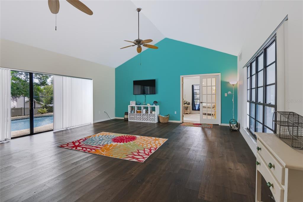 A living room features dark wood floors, a teal accent wall, and a sliding glass door — 34007 SABAL WAY, LEESBURG, FL