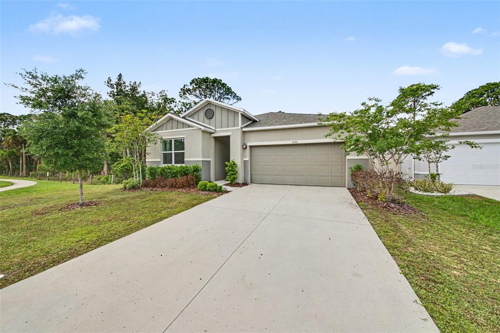 A single-story house with a beige exterior, a two-car garage, and a concrete driveway — 7646 TURCHETTA COURT, TITUSVILLE, FL