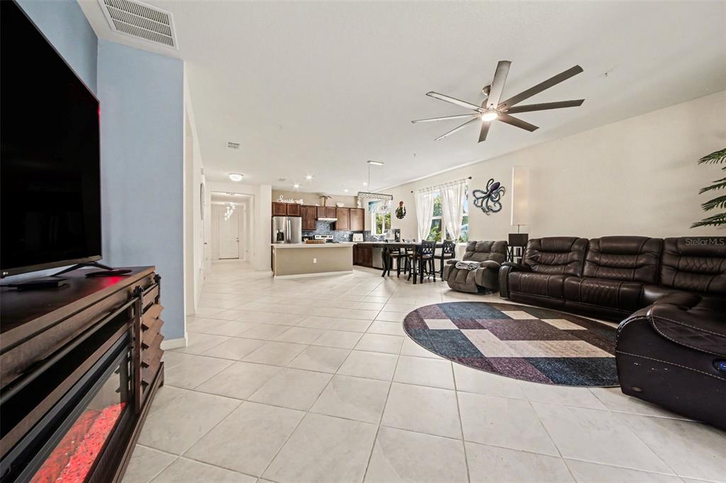 An open-concept living room and kitchen featuring tile flooring, a ceiling fan, and leather furniture — 7646 TURCHETTA COURT, TITUSVILLE, FL