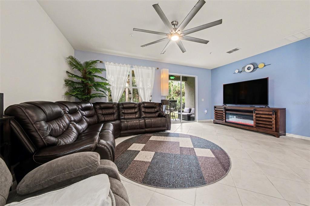 A living room features a large brown sectional, a circular rug, and a wall-mounted television — 7646 TURCHETTA COURT, TITUSVILLE, FL