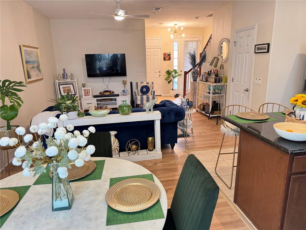 An open-concept living and dining area features a blue sofa, bar cart, and kitchen island — 4838 MATTEO TRAIL, ORLANDO, FL