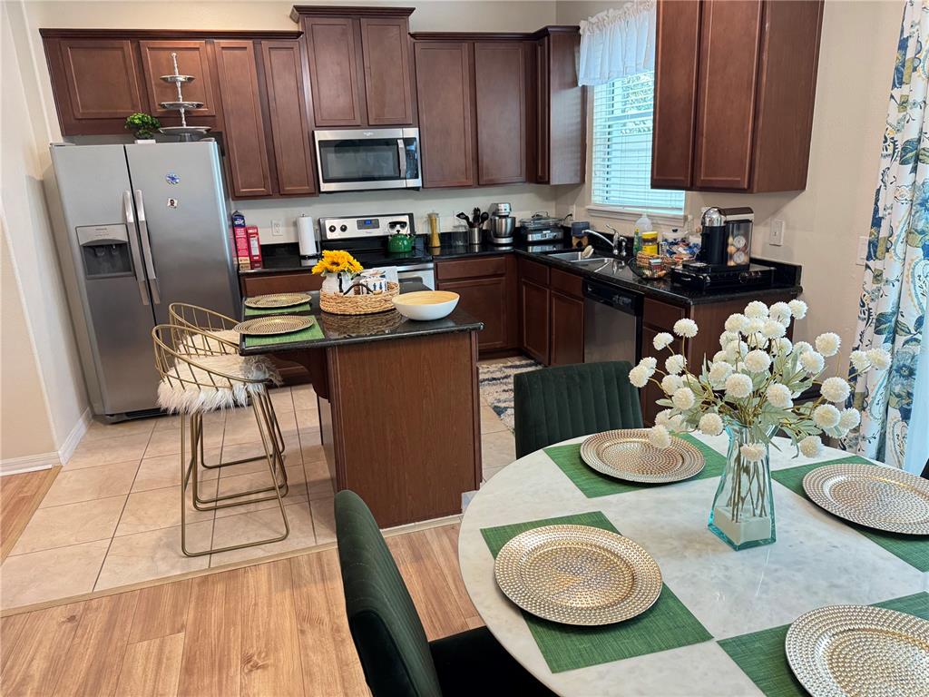 A kitchen features dark wood cabinets, black countertops, a center island, and a dining area — 4838 MATTEO TRAIL, ORLANDO, FL