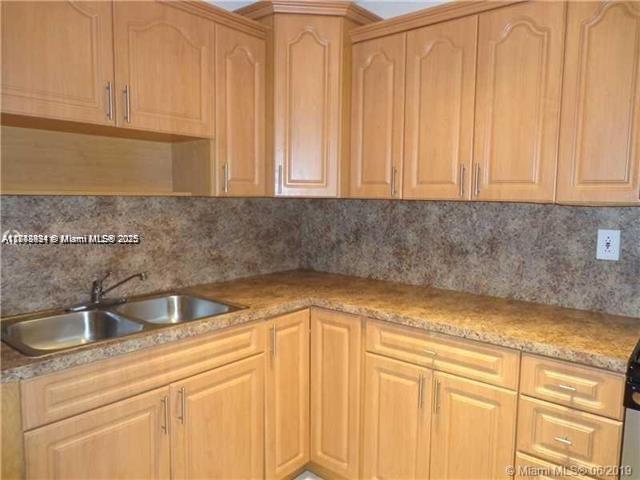 A kitchen features light wood cabinets, a double-basin sink, and a speckled brown laminate countertop — 15225 NE 6th Ave # B207, Miami FL 33162, MIAMI, FL