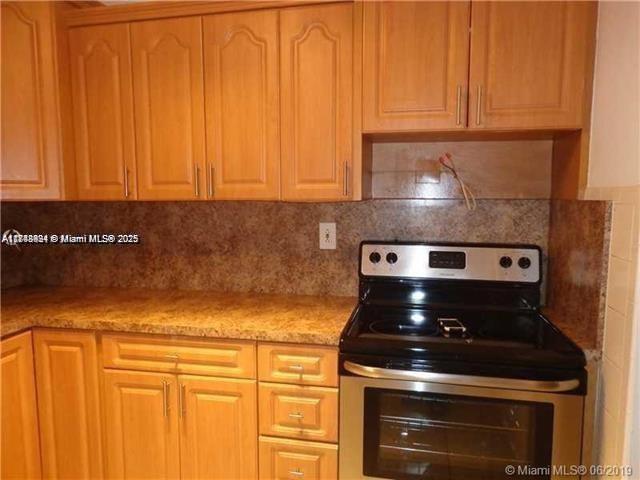 A kitchen features light wood cabinets, a dark countertop, and a stainless steel electric stove — 15225 NE 6th Ave # B207, Miami FL 33162, MIAMI, FL