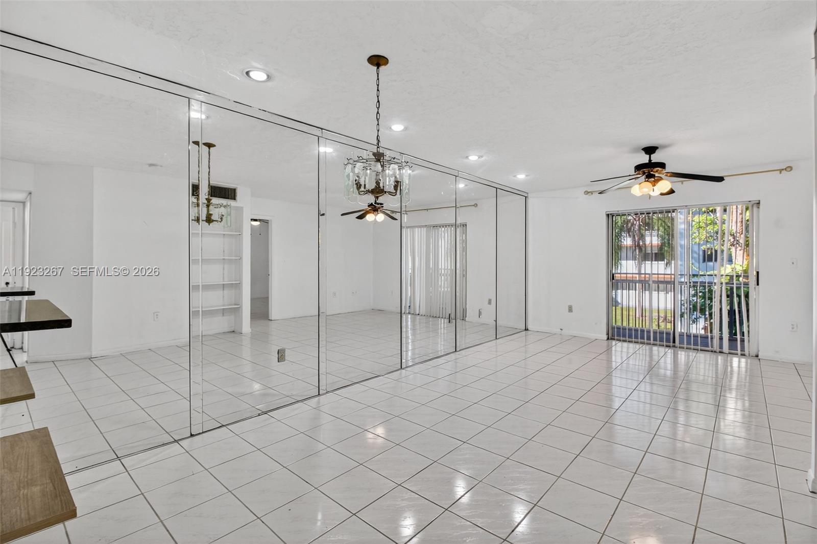 A bright room features white tile flooring, a mirrored wall, and a ceiling fan — 11309 SW 200th St # C, Miami FL 33157, MIAMI, FL