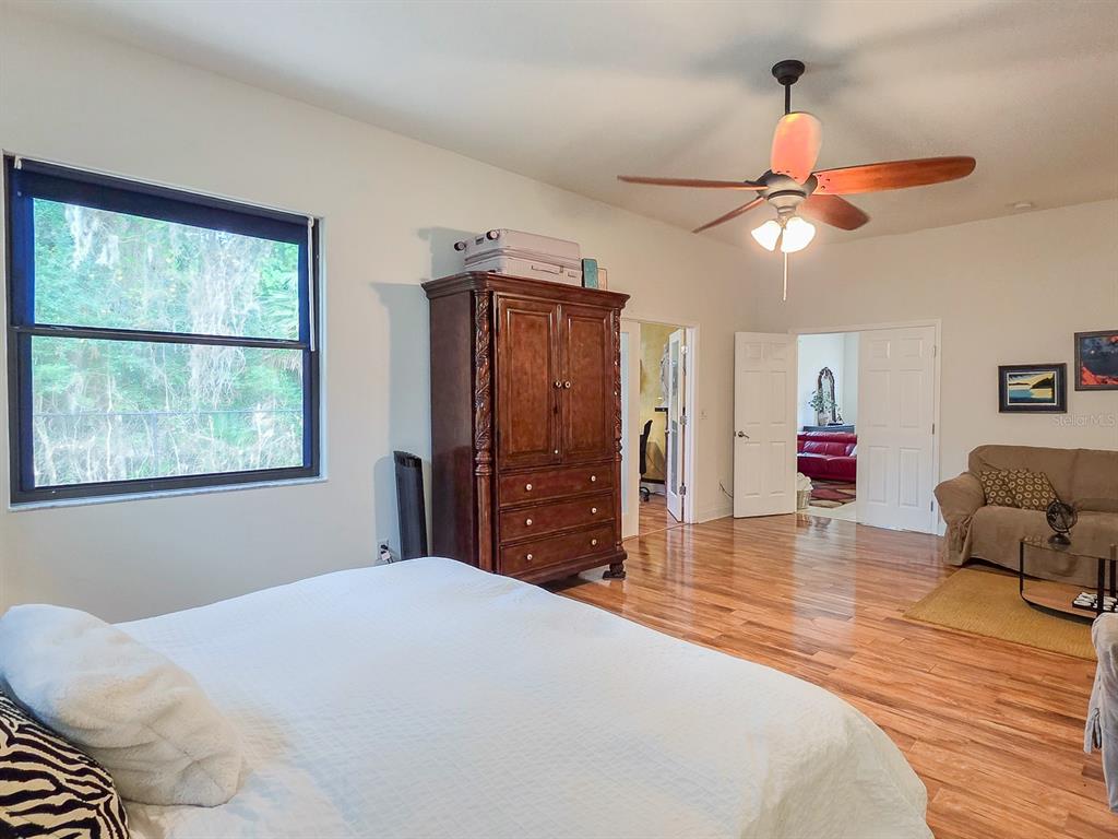 A bedroom with hardwood floors, a large wooden armoire, and a ceiling fan — 13 RIVER OAKS WAY, PALM COAST, FL
