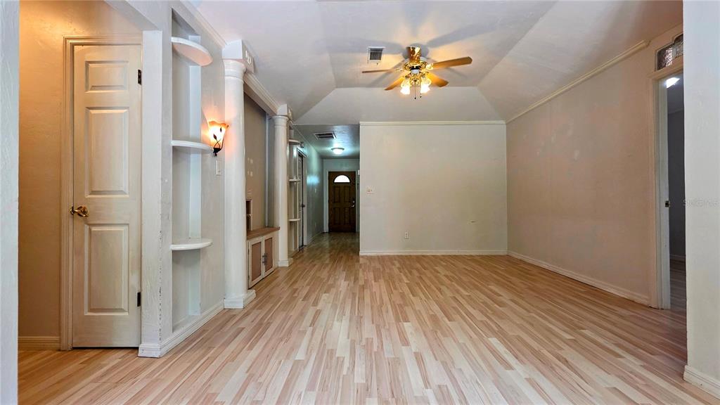 A room with light wood-look flooring, a ceiling fan, and built-in shelving with columns — 3741 NW 59TH PLACE, GAINESVILLE, FL