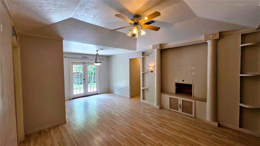 A living room with light wood flooring, a tray ceiling, and a built-in media center — 3741 NW 59TH PLACE, GAINESVILLE, FL