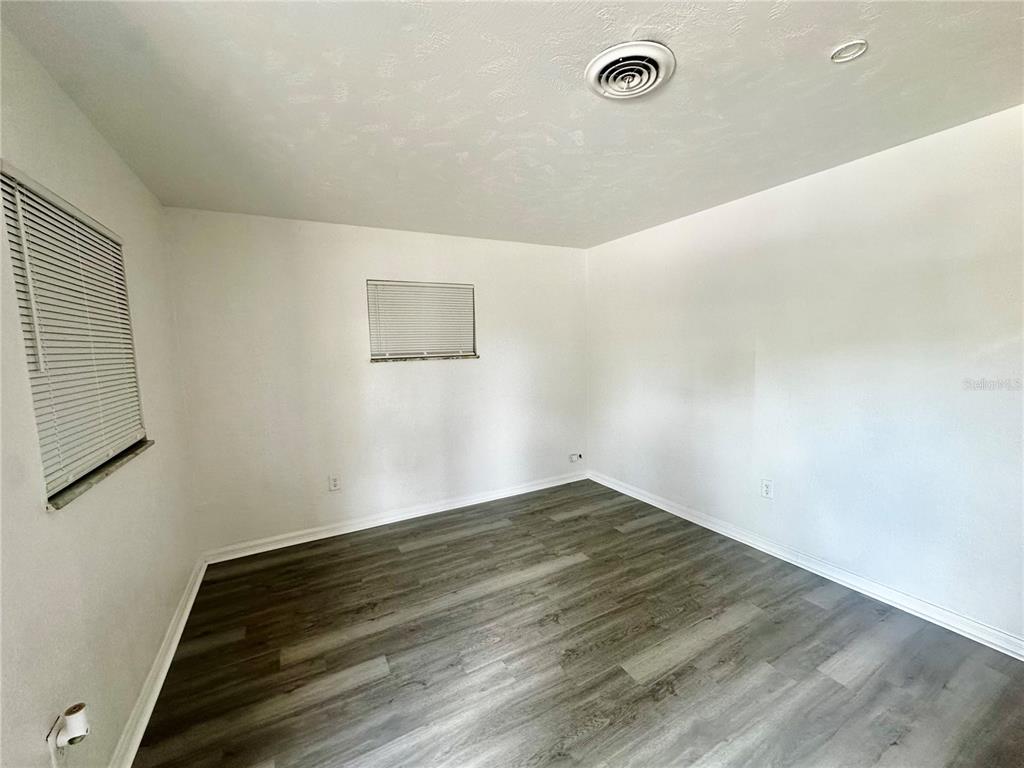 An empty bedroom features white walls, gray wood-look flooring, and two windows with blinds — 5527 BRYSON DRIVE, ORLANDO, FL