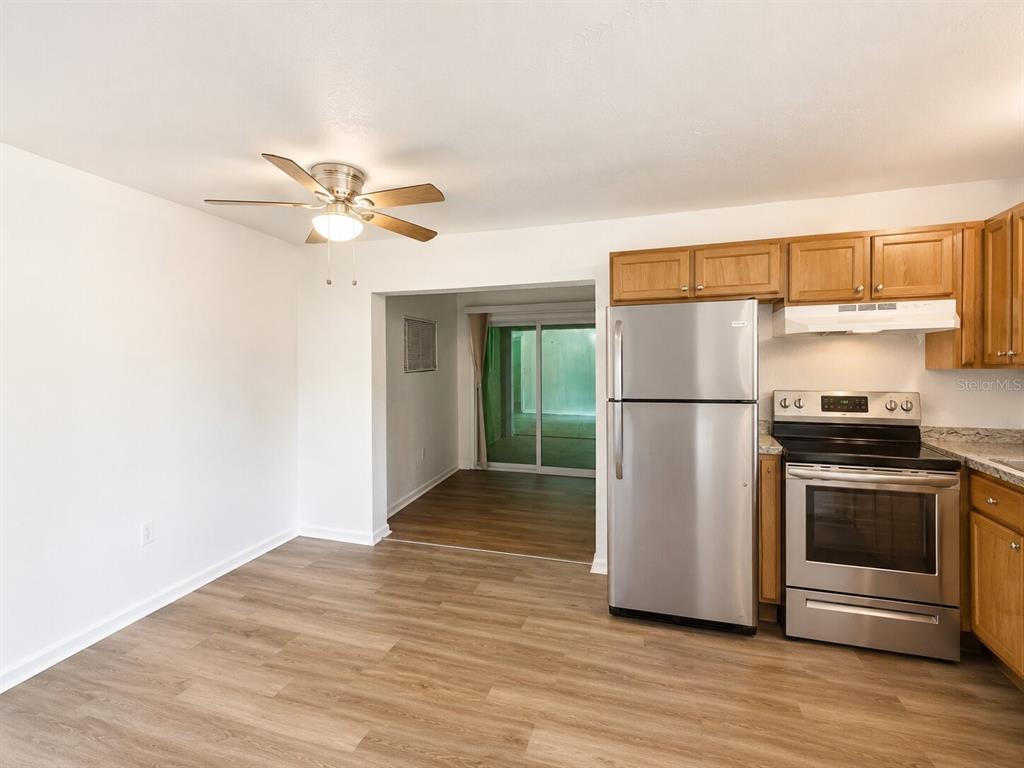 A kitchen with wood cabinets, stainless steel appliances, and light wood-look flooring — 5527 BRYSON DRIVE, ORLANDO, FL