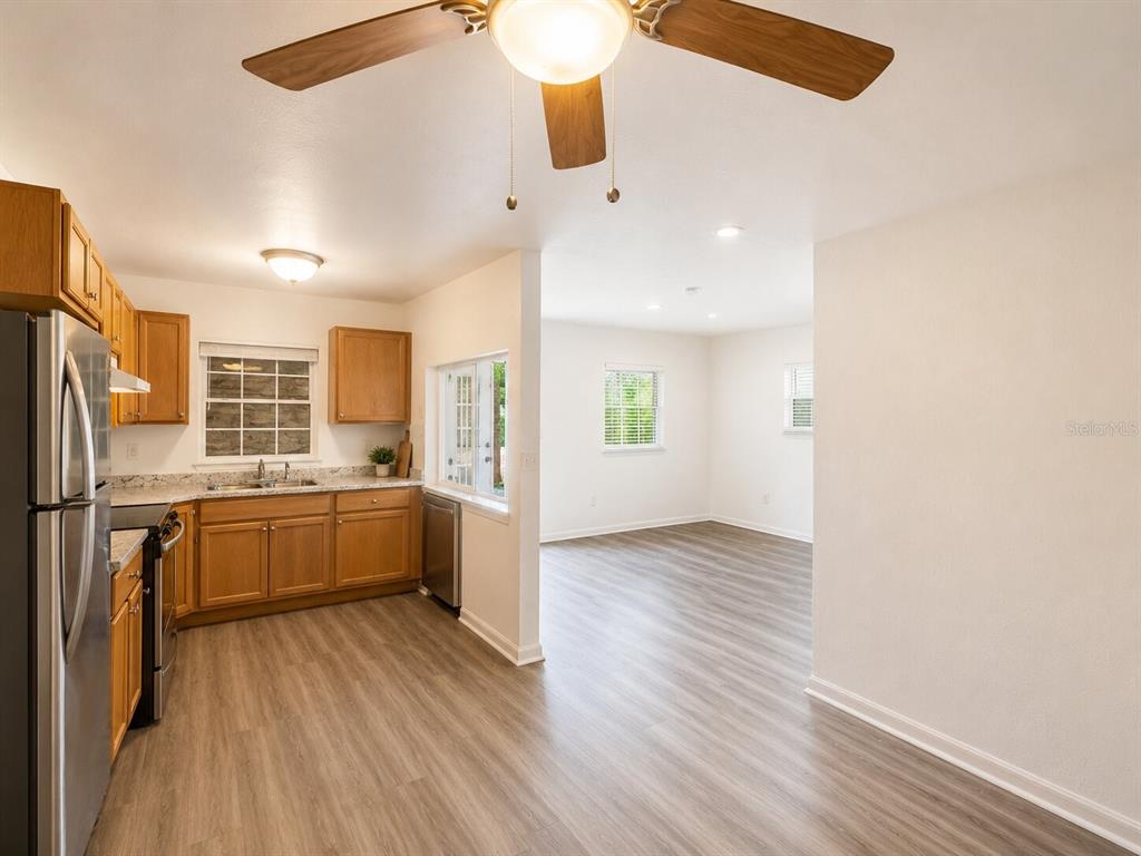 A kitchen with wood cabinets and stainless steel appliances opens into a living area — 5527 BRYSON DRIVE, ORLANDO, FL