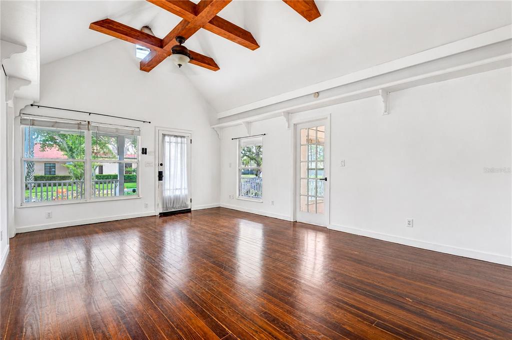 A bright room with vaulted ceilings, exposed wooden beams, hardwood floors, and multiple glass doors — 1512 OREGON STREET, ORLANDO, FL