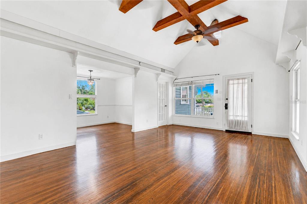 A bright living room with hardwood floors, vaulted ceilings, exposed wooden beams, and a ceiling fan — 1512 OREGON STREET, ORLANDO, FL