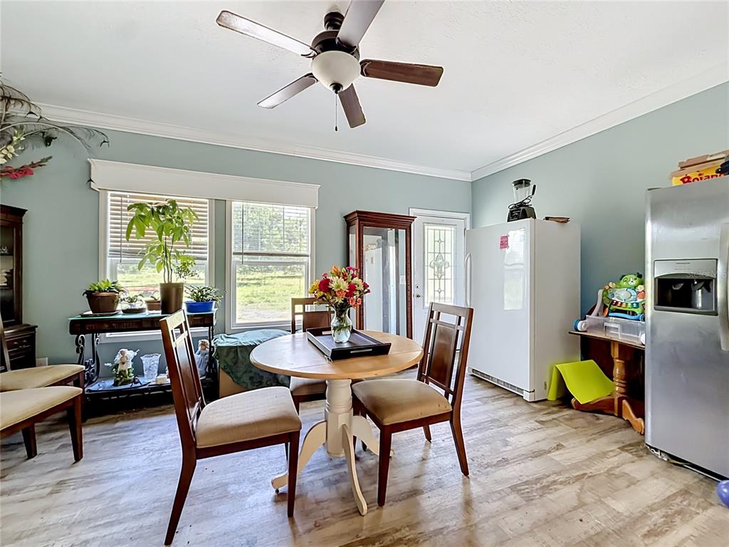 A dining area features a round wooden table, chairs, light blue walls, and wood-look flooring — 1689 NE 189TH LANE, CITRA, FL