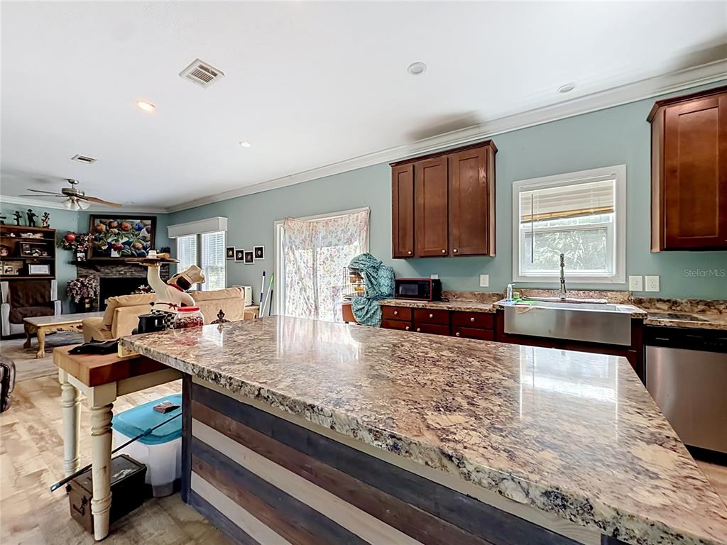 A kitchen with a large granite-topped island, dark wood cabinets, and a farmhouse sink — 1689 NE 189TH LANE, CITRA, FL