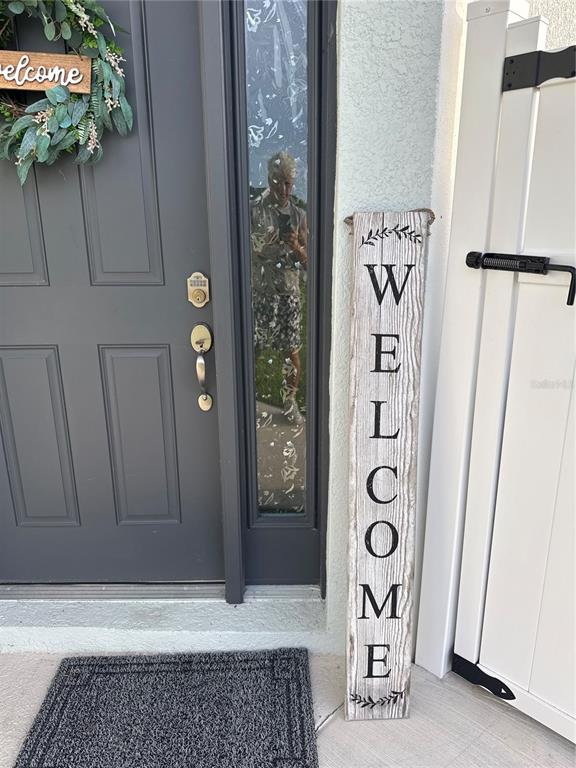 A gray front door with a welcome sign stands next to a white fence — 1867 NOTTINGHAM TRAIL, PUNTA GORDA, FL