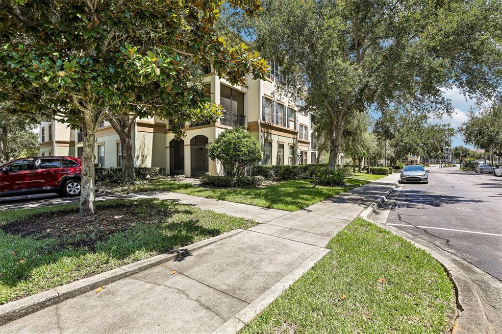 A multi-story apartment building with screened balconies sits beside a sidewalk and a street — 11564 MIZZON DRIVE UNIT 102, WINDERMERE, FL