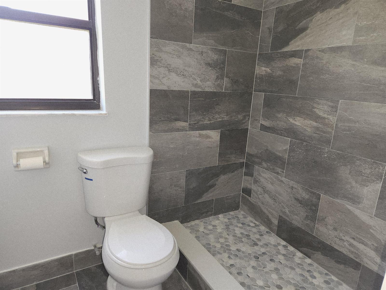 A bathroom features a white toilet, a walk-in shower with gray tile, and hexagon flooring — 2050 Oleander Boulevard # 109, Fort Pierce FL 34950, FORT PIERCE, FL