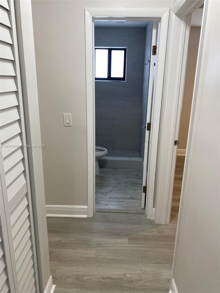 A view through a doorway shows a bathroom with gray tile flooring and walls — 4650 W Flagler St # 3, Miami FL 33134, MIAMI, FL