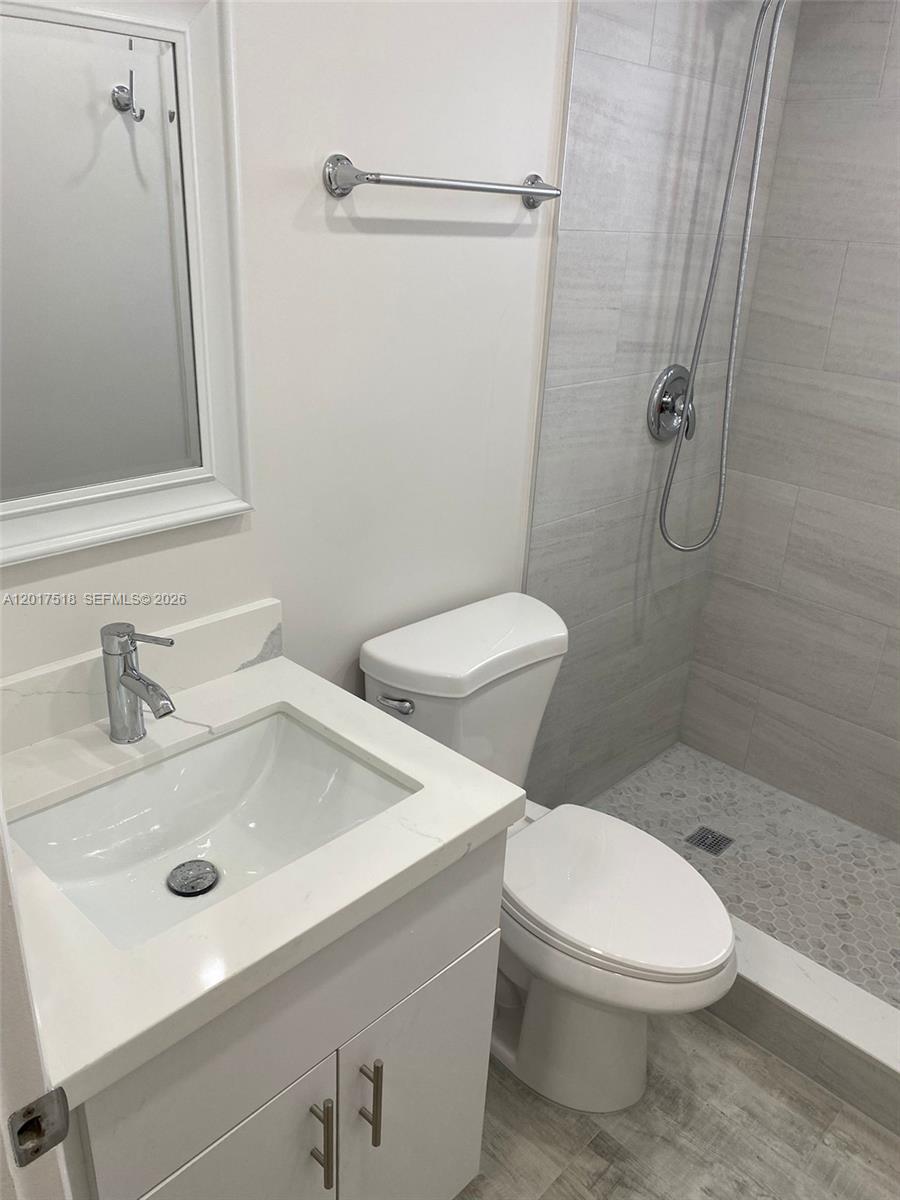 A bathroom features a white vanity, a toilet, and a tiled walk-in shower — 4650 W Flagler St # 3, Miami FL 33134, MIAMI, FL