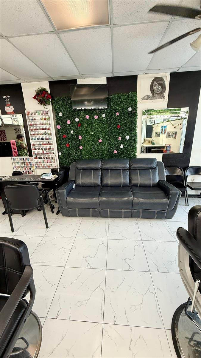 A salon waiting area features a dark leather sofa, a green wall, and tiled floors — 11842 W Dixie Hwy, Miami FL 33161, MIAMI, FL