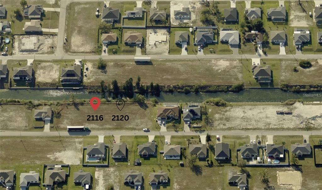 This aerial view shows two adjacent vacant residential lots situated along a canal — 2116 NW 17TH AVENUE, CAPE CORAL, FL