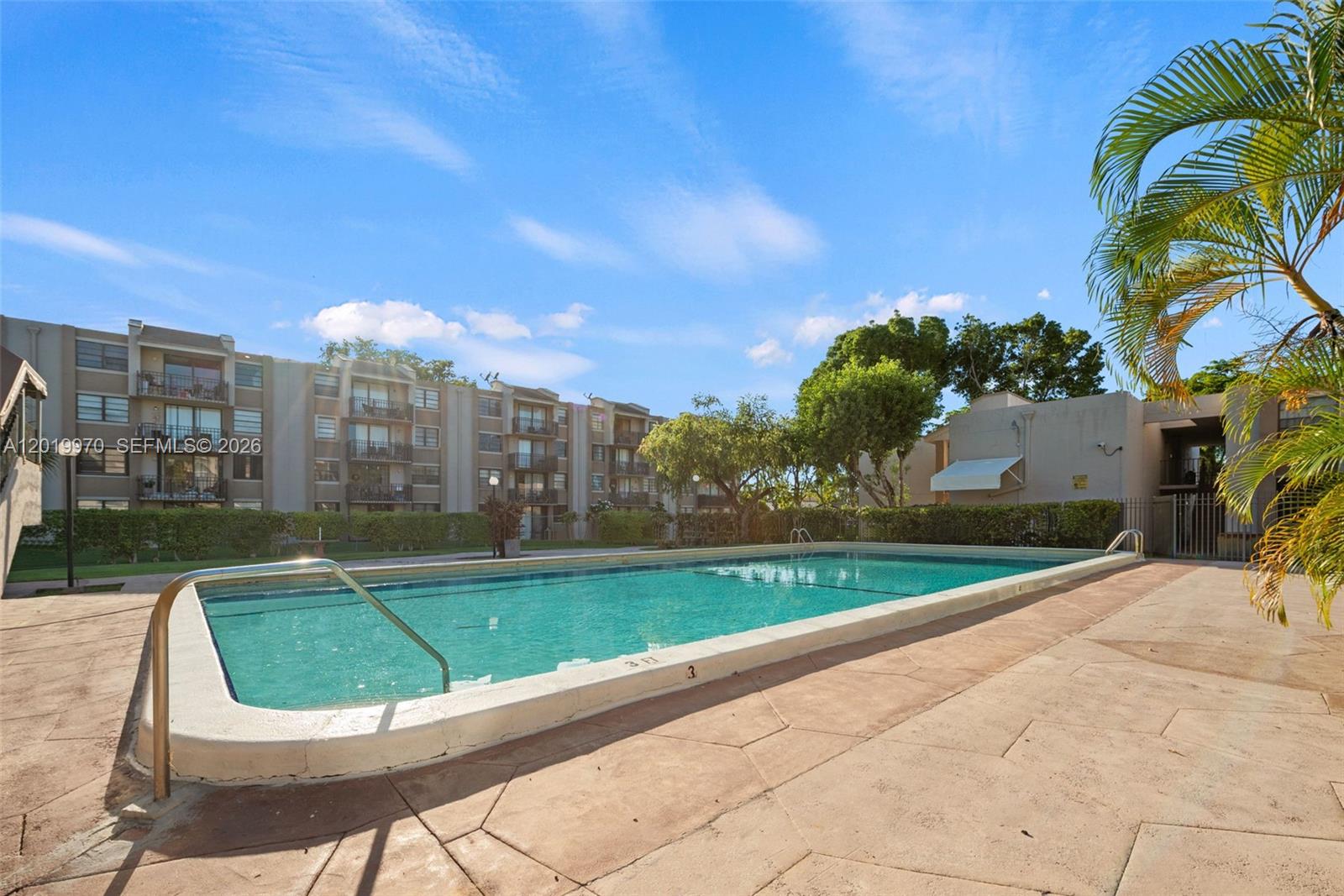 An outdoor swimming pool is surrounded by a concrete deck and a multi-story apartment building — 3581 SW 117th Ave # 206, Miami FL 33175, MIAMI, FL